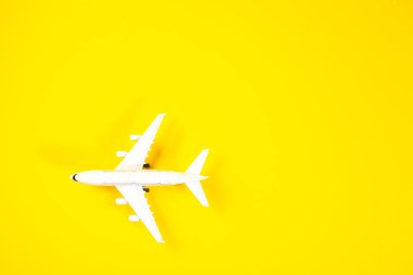 Sarı arka planda beyaz oyuncak uçak. Asgari seyahat kavramı.