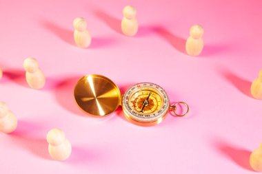 Pusula ve pembe arka plandaki insanların tahta figürleri. Doğru yönü bulma kavramı..