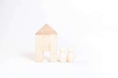 Tahta insan figürleri ve beyaz arka planda bir ev. Gayrimenkul alıp satma kavramı.