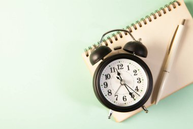 Siyah saat ve beyaz arkaplan içeren not defteri