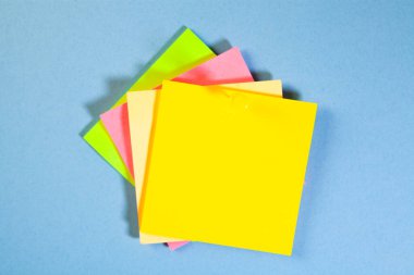 Mavi arkaplanda izole edilmiş renkli yapışkan notlar ve metin için boşluk.