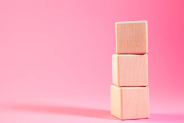 Pembe arka planda tahta küpler. Metnin için yer.