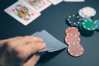 Poker fişleri ve kartları siyah bir masada, yakın plan.