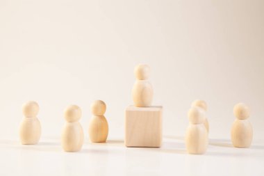 Tahta figürler beyaz arka planda duruyor. Liderlik ve takım çalışması kavramı.