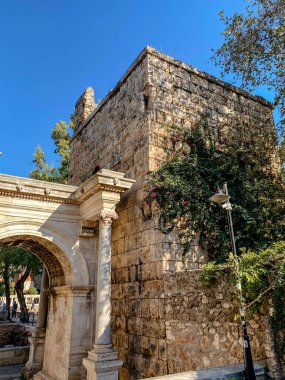Antalya, Türkiye 'deki Hadrian Kapısı. Eski Roma zafer kemeri ve Kaleici eski kasabasının taş duvarları berrak mavi gökyüzünün altında.