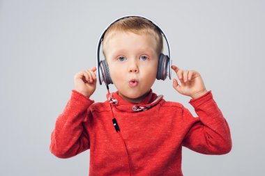 Küçük çocuk kırmızı kazak (gri izole kulaklık onun müzik keyfi)