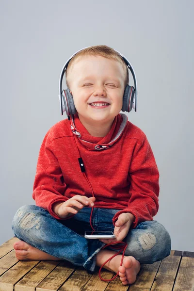 Улыбающийся мальчик закрывает глаза, слушая музыку. . — стоковое фото