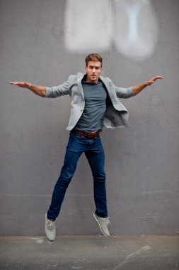 Gri duvar karşısında hop ifadesinde mavi ceketli trendy şık çocuk