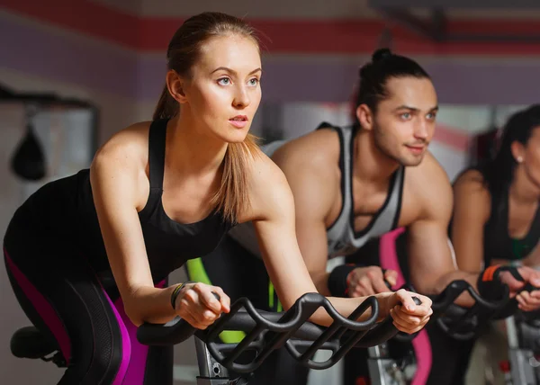 Group of young people cycling in class in gym — Stock Photo, Image