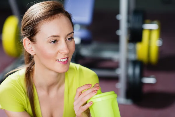 Portrait of young women with a bottle of water in her hand and looking aside — Stock Photo, Image