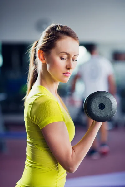 Young fit woman lifting dumbbell in gym. — Stock Photo, Image