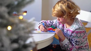 Noel Baba 'ya yeni yıl tatili için mektup yazan çocuk, rahat Noel süslemeleri ve ışıkları, renkli kalemler çizen kız, Noel Baba' ya hediyeler hazırlayan çocuk,