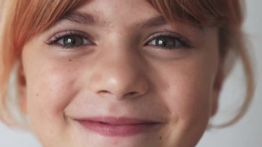 Yakın plan, mutlu beyaz kız ilkokulda kızıl saçlı, gülümseyen, gri gözlü. Kameraya bakıyorum. Pozitif ruh hali, neşeli, neşeli çocuk, beyaz arka planda gül.