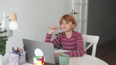 Ortaokul kızıl saçlı, beyaz öğrenci kız öğrencileri laptop kullanıyor. Uzaktan öğrenme çevrimiçi eğitim. Liseli kız evde dijital tablet bilgisayarla el yazısı yazıyor ve okul ödevi yapıyor..