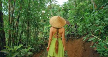 Bali 'de sık bambu ormanlarında yürüyen yaz elbiseli bir kadın..