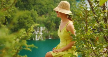 Yazın Plitvice Gölleri Ulusal Parkı 'ndaki şelaleye huzurlu bir şekilde bakan bir kadın..