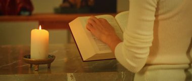 Mermer sunakta mum ışığında kutsal kitabı okuyan kişi.