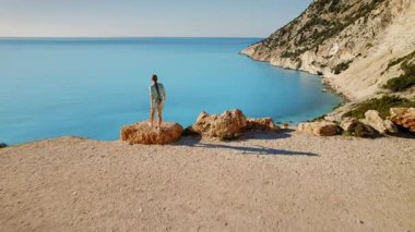 Yunanistan 'da sakin bir körfeze bakan Turkuaz İyon Denizi' nin yanına park etmiş arabasıyla uçurum kenarına doğru koşan kadın.