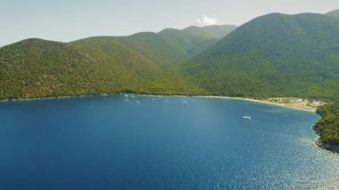 Yunanistan 'da yaz aylarında yemyeşil bir körfez yakınlarında demirlemiş yelkenlilerin hava manzarası.