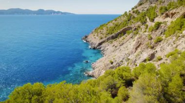 Turkuaz kıyı suları Kefalonia 'da kayalık kayalıklarla ve yeşil çam ormanlarıyla buluşuyor..