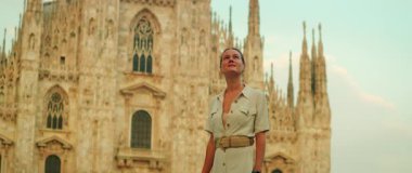 Kadın, Milano 'da sıcak bir yaz gökyüzünün altındaki Gotik katedrale hayranlıkla bakıyor..