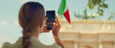 Turist, Arco della Pace 'in yaz günü İtalyan bayrağıyla çekilmiş bir videosunu kaydediyor..