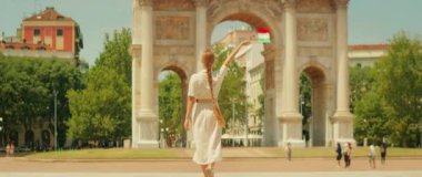 İtalyan bayrağını sallayan ve yaz boyunca Milan 'da tarihi bir kemer olan Arco della Pace' e doğru yürüyen kadın..