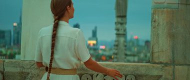 Modern Milan şehrine hayran olan bir kadın alacakaranlıktaki tarihi çatıdan gökyüzü manzaralı..