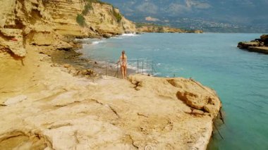 Kayalık kayalıklarda yürüyen ve Kefalonya 'daki İyon Denizi' ne bakan bir kadın..