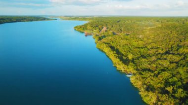 Meksika 'daki Bacalar lagünündeki derin mavi su ve orman manzarası..