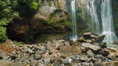Kosta Rika 'da ormanla çevrili Nauyaca şelalesinin yanındaki kayalarda duran çift..