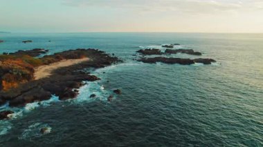 Kosta Rika 'da gün batımında dalgaların engebeli kıyılara vurduğu Rocky sahili..