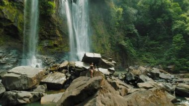 Kosta Rika ormanlarında dev kayaları ve çağlayan şelaleleri keşfeden bir kadın..