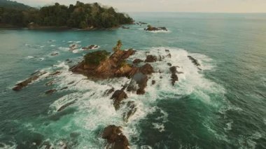 Pasifik Okyanusu dalgaları, Kosta Rika 'nın Dominicalito sahilinde kayaların üzerinde süzülür..