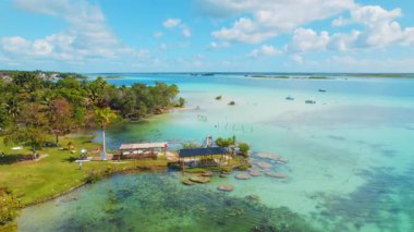 Meksika 'da sığ turkuaz sularda rıhtım ve tekneleri olan Bacalar Lagünü kıyısı.