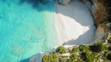 Yunanistan 'da turkuaz sular ve kayalıklarla çevrili tenha beyaz kumlu plaj.