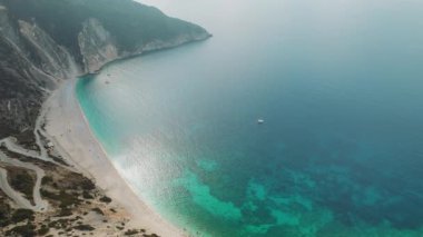 Yunanistan 'ın turkuaz deniz sularında teknesi olan uzun sahil ve uçurumların havadan görünüşü.