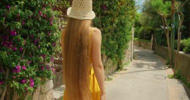 Güneşli bir yaz günü Capri 'de sessiz çiçekli Camerelle' i keşfeden kadının arka görüntüsü.