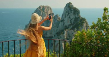 Faraglioni kayalarının akıllı telefon fotoğraflarını çeken kadının yakın görüntüsü ve Capri İtalya 'da açık deniz..