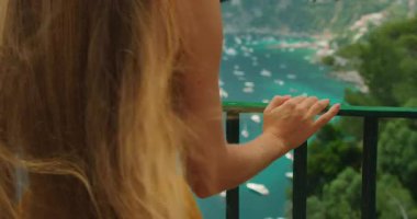 Kadın, Capri İtalya 'daki turkuaz körfez ve teknelere el uzatıyor..