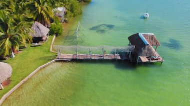 Meksika 'daki tropik palmiyelerin oradaki turkuaz lagünün üzerinde yürüyen bir kadın..