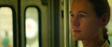 Trenin camından dışarı bakan bir kadın sakin ve düşünceli bir ifadeyle.