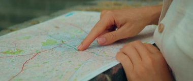 Yazın bir şehri keşfederken haritada bir yeri gösteren bir kadın..