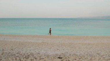 Yunanistan 'da Kefalonia' da sakin turkuaz sabah denizi kenarında koşan bir kadın.