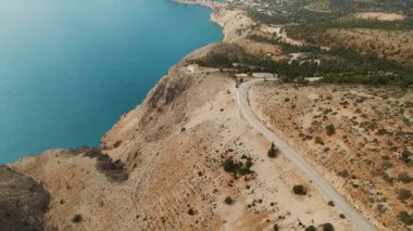 Turkuaz denizin üzerindeki kayalık yol ve sakin Akdeniz manzaralı Kefalonia Adası 'ndaki Asos köyü..