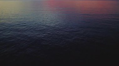 Yumuşak akşam renkleri, Yunanistan 'ın Kefalonya açıklarındaki sakin İyon Denizi ufkunu yansıtıyor.