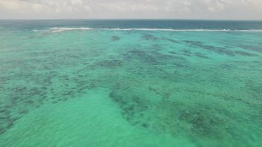 Yukardan turkuaz su vasıtasıyla görülebilen mercan yamaları ile açık ve sığ okyanus.