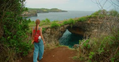 Sırt çantalı gezgin kadın Bali Nusa Penida 'da Kırık Kumsal' a doğru yürüyor..