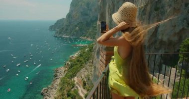 Yaz rüzgarlı bir günde İtalya 'nın başkenti Capri' de Marina Piccola 'nın sahil şeridini fotoğraflayan turist kadın..