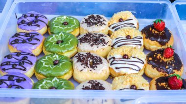 Çeşitli aromalı ve malzemeli çörekler. Konteynıra yerleştirilmiş bir donut koleksiyonu..